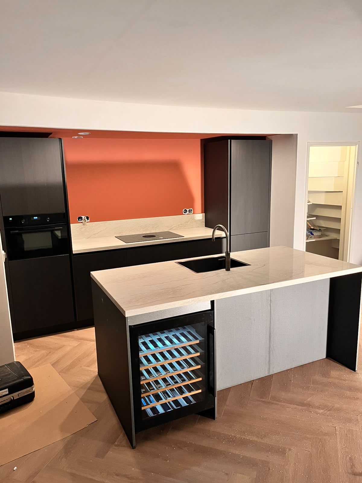 Donkere keuken met wijnkoeler en terracotta achterwand