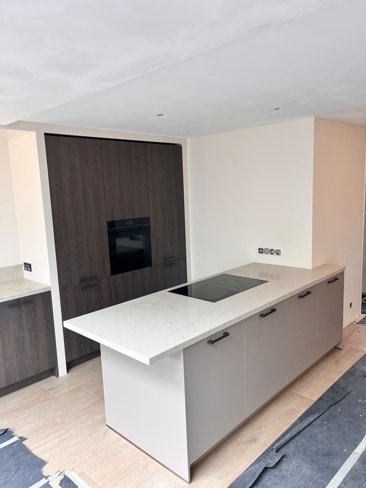 Keuken met donker houten kastenwand en licht eiland