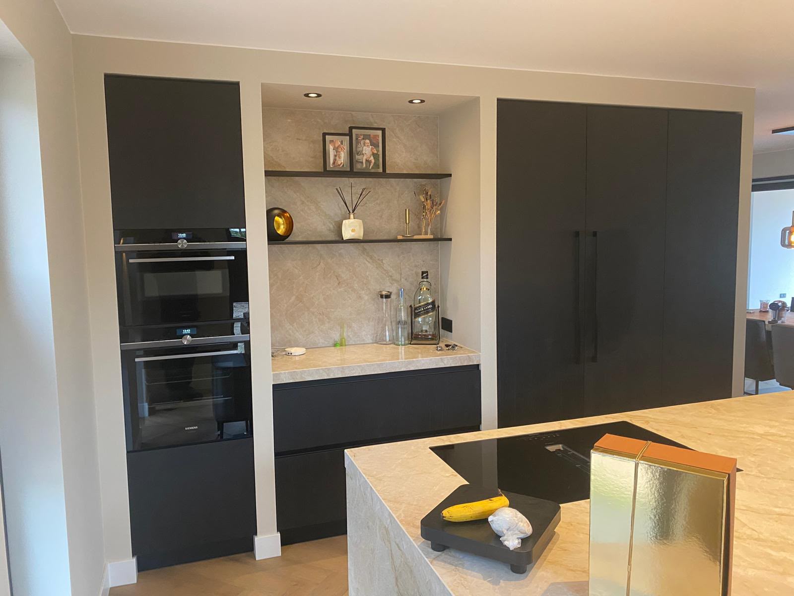 Zwarte keuken met nis, schappen en dubbele oven