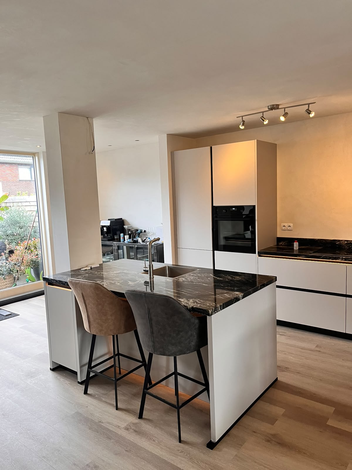Witte keuken met donker marmeren eiland en barkrukken